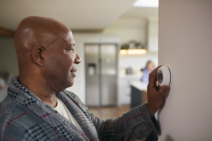 man turning the control dial on thermostat