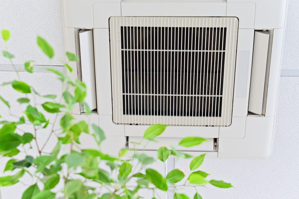 Ceiling air conditioner in modern office or at home with green ficus leaves