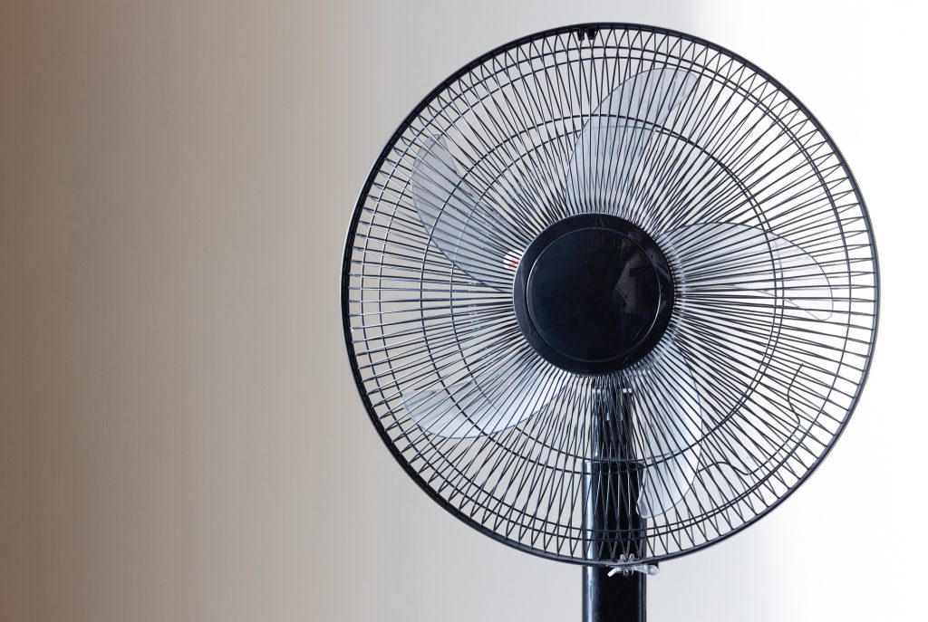 Closeup on electric floor standing fan in the modern living room in sunny hot summer day.