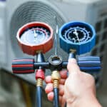 Technician checking air conditioning operation, detecting refrigerant leaks.